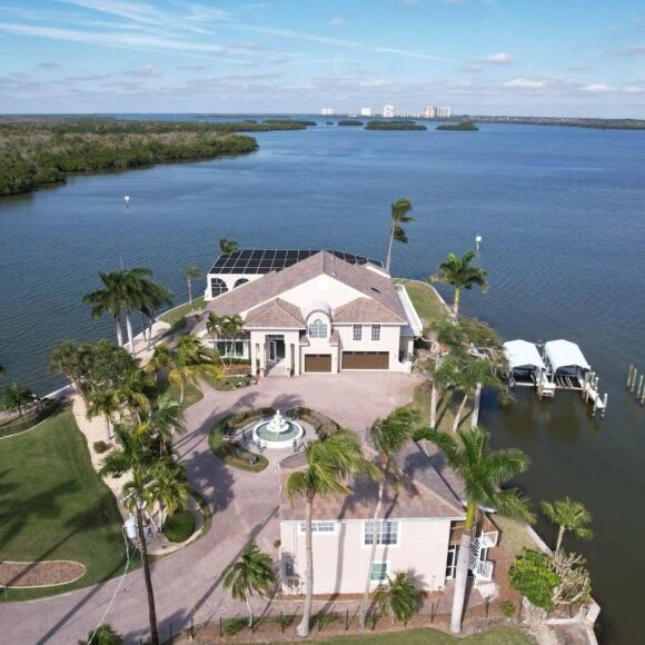 Wide aerial drone shot of an exclusive peninsula estate in Sarasota County with a premium concrete tile roof and integrated solar panel array, serviced by Legrand's Roofing.