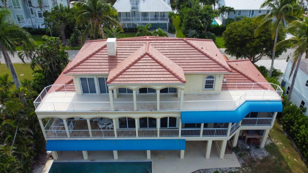 Elevated drone view of a multi-story coastal home in Charlotte County featuring a newly installed terracotta Spanish tile roof by Legrand's Roofing & Construction LLC.