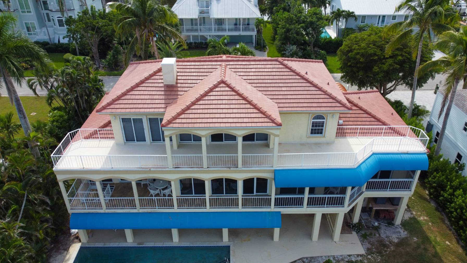 Elevated drone view of a multi-story coastal home in Charlotte County featuring a newly installed terracotta Spanish tile roof by Legrand's Roofing & Construction LLC.