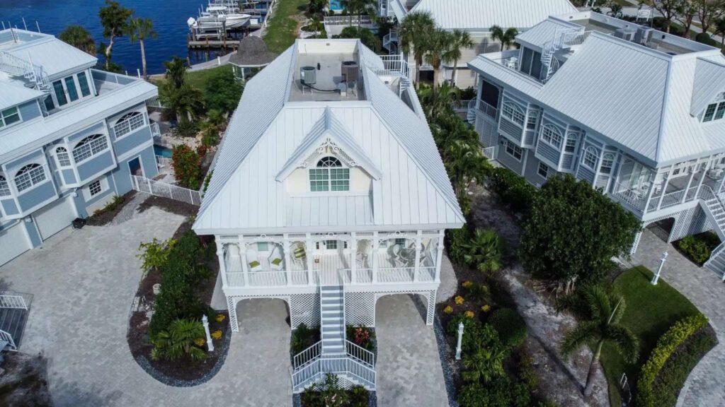 Aerial view of a coastal home featuring a high-reflectivity white standing seam metal roof installed by Legrand's Roofing & Construction LLC in Lee County