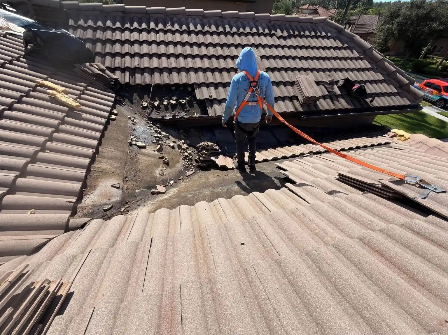 Professional roofer inspecting and repairing a leaking tile roof valley with damaged underlayment on a residential home.