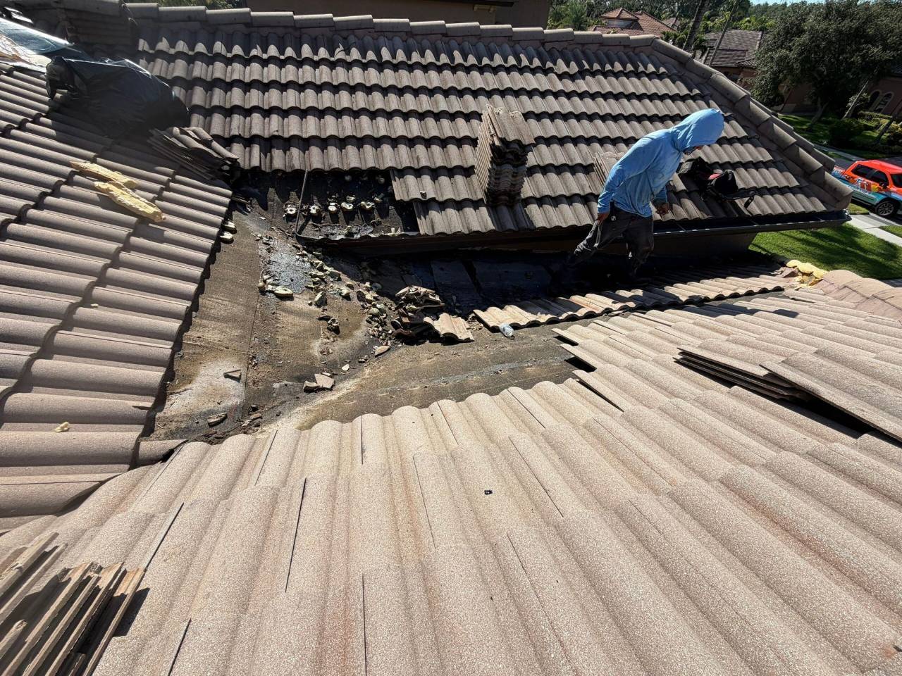 Professional roofer inspecting and repairing a leaking tile roof valley with damaged underlayment on a residential home.