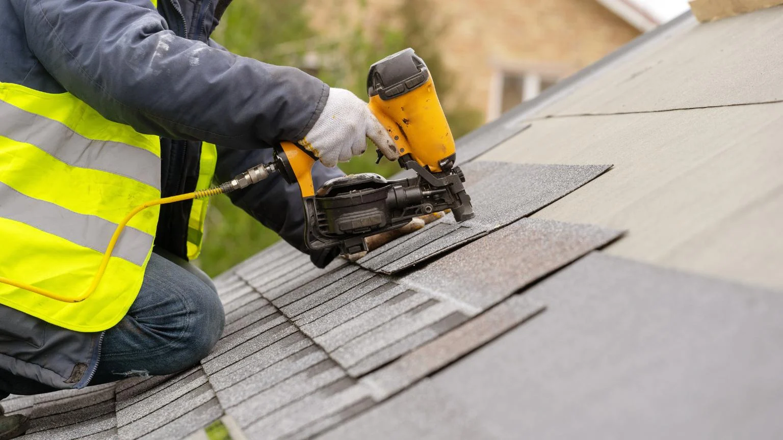Close-up of a roofer using a pneumatic nail gun to complete a shingle roof repair with precision craftsmanship.