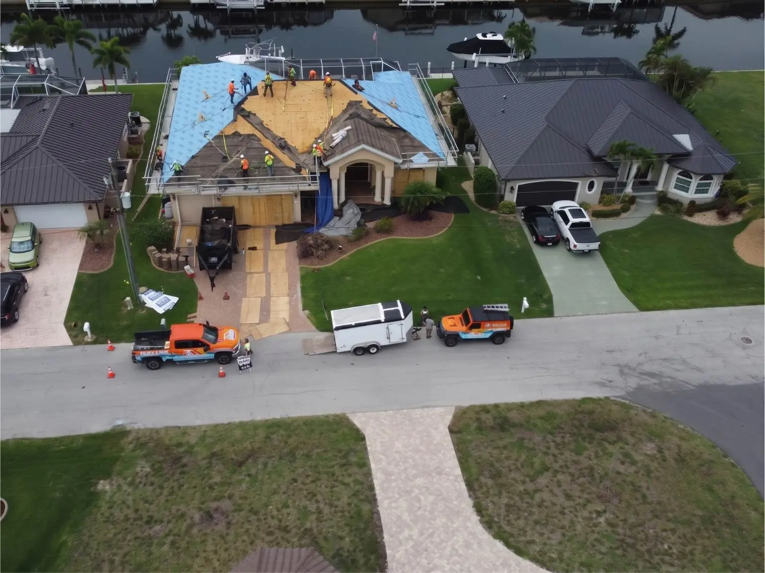 Full aerial neighborhood view showing Legrand's Roofing service trucks and an active underlayment installation on the 217 re-roofing site.