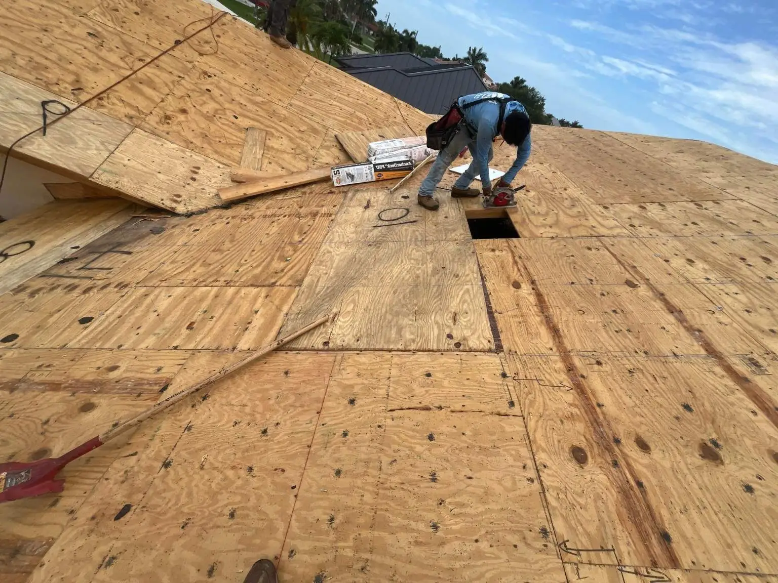 A technician from Legrand's Roofing uses a circular saw to trim wood sheathing during the 217 re-roof installation phase.