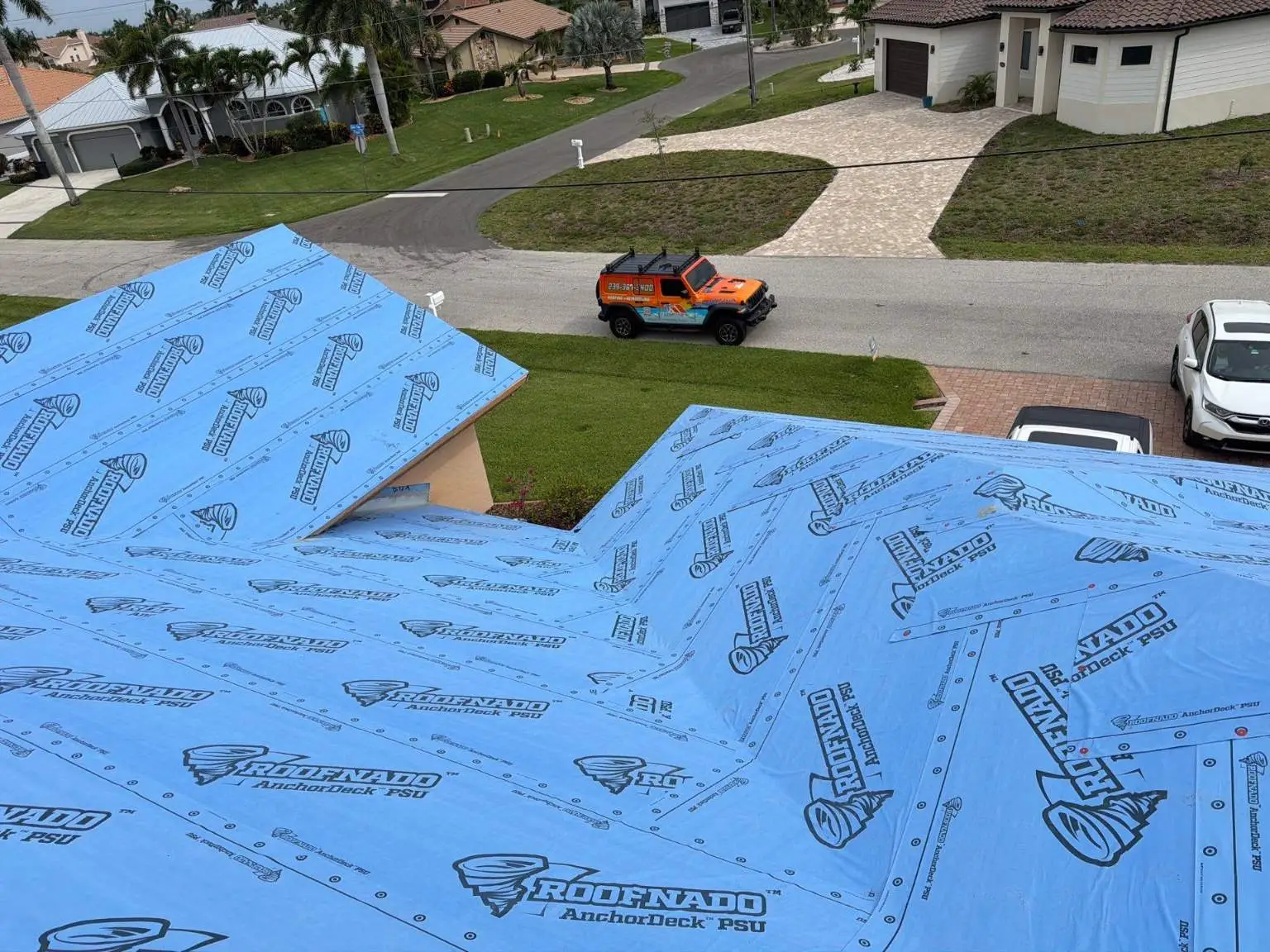 Elevated view of a residential roof fully wrapped in blue Roofnado AnchorDeck PSU self-adhered underlayment by Legrand's Roofing.