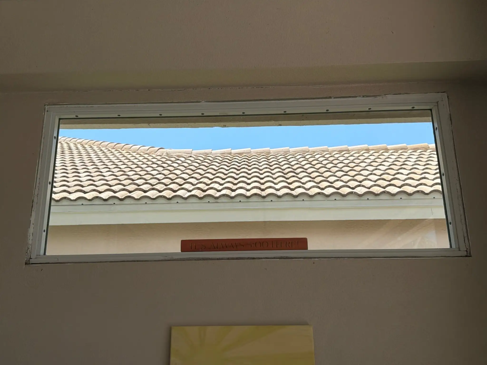 A clear transom window reflecting the main concrete tile roof architecture above, documented during an exterior leak assessment on June 12.