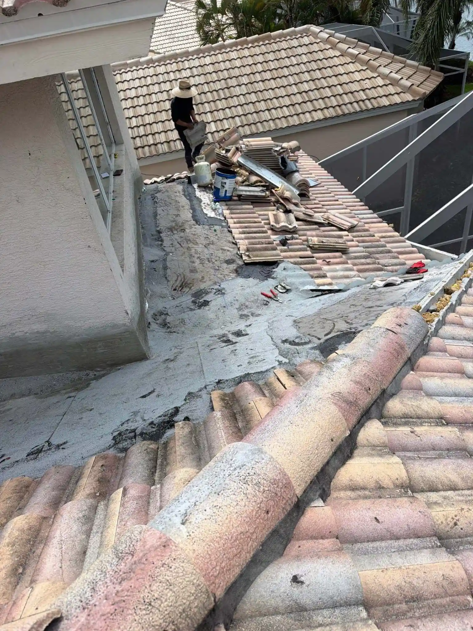 Legrand's Roofing technician working on a stripped flat section of a roof system, staging tiles and equipment on June 19.