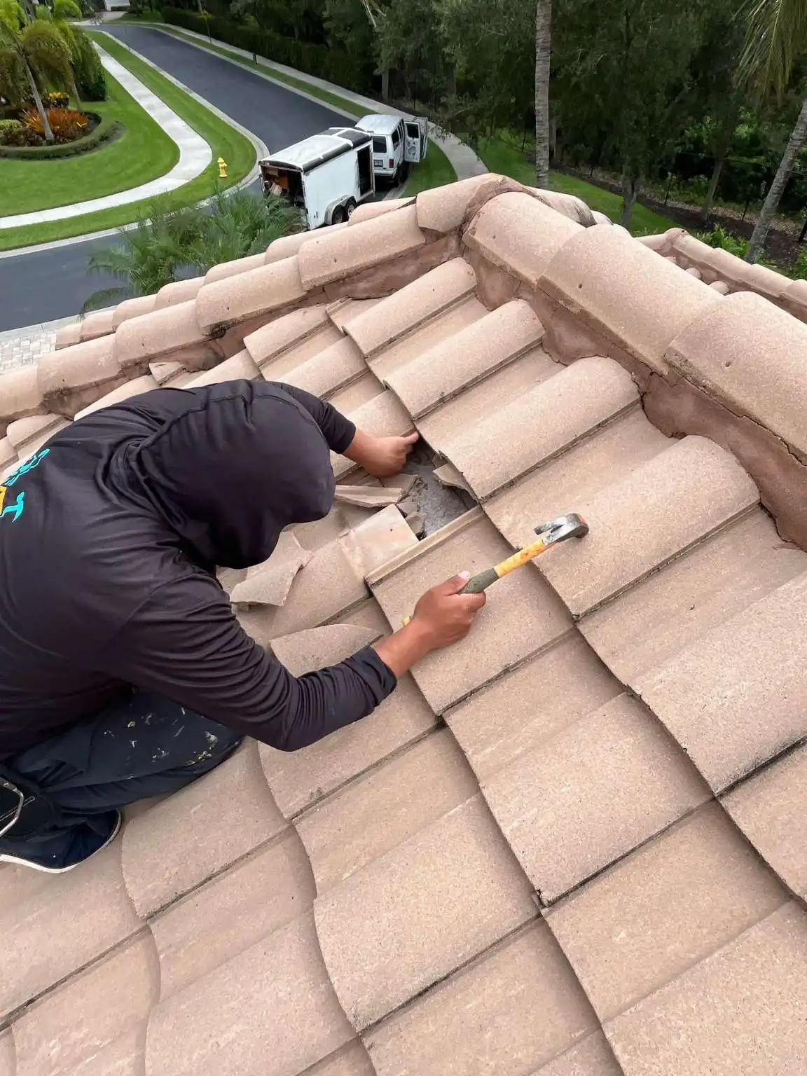 A Legrand's Roofing repair specialist utilizes a framing hammer to carefully remove damaged mortar mix and cracked tile fragments on the Sally Craft roof ridge.
