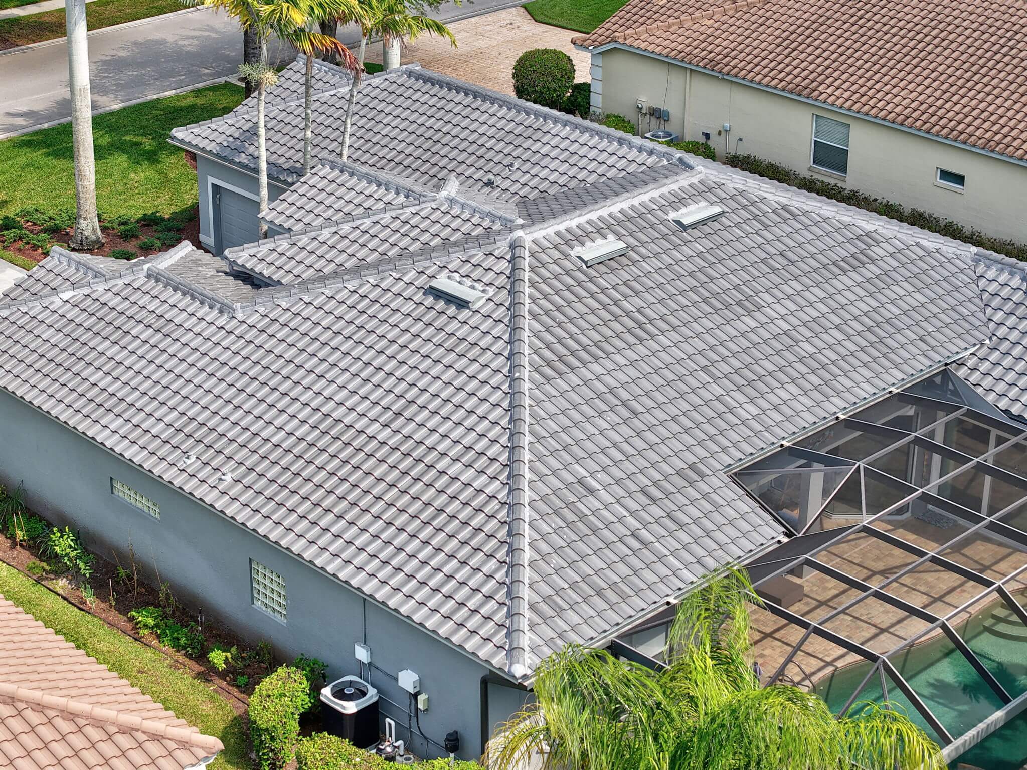 Angled side aerial shot focusing on skylights, roof ridges, and grey tile installation craftsmanship.