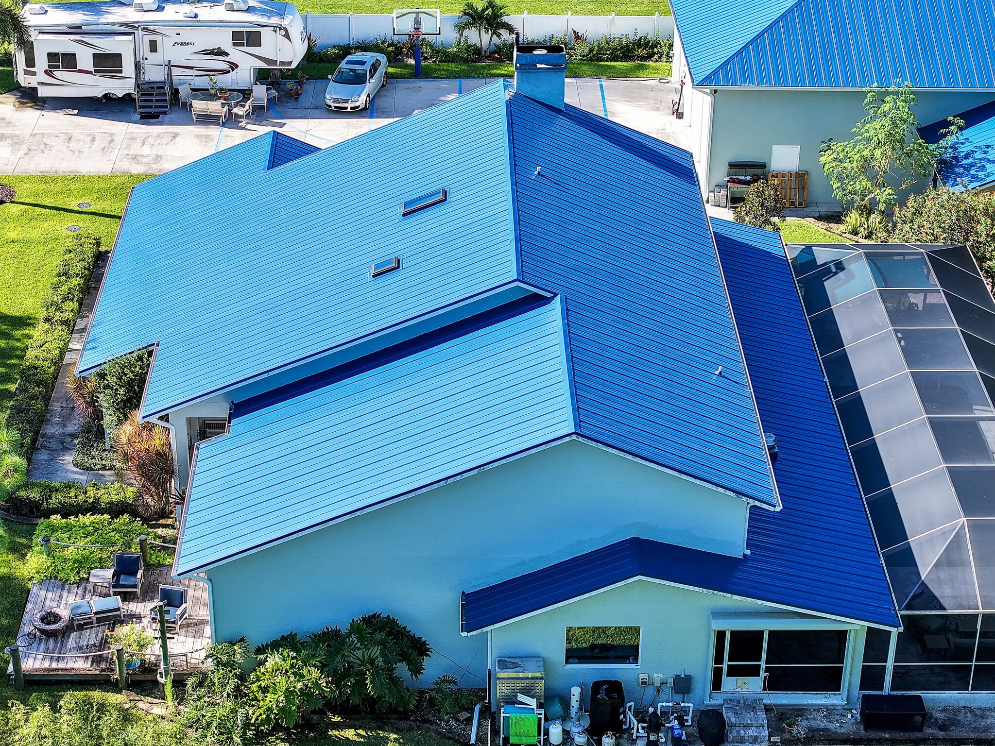 Close-up drone shot focusing on the rear-view of the main house and its blue metal roof.