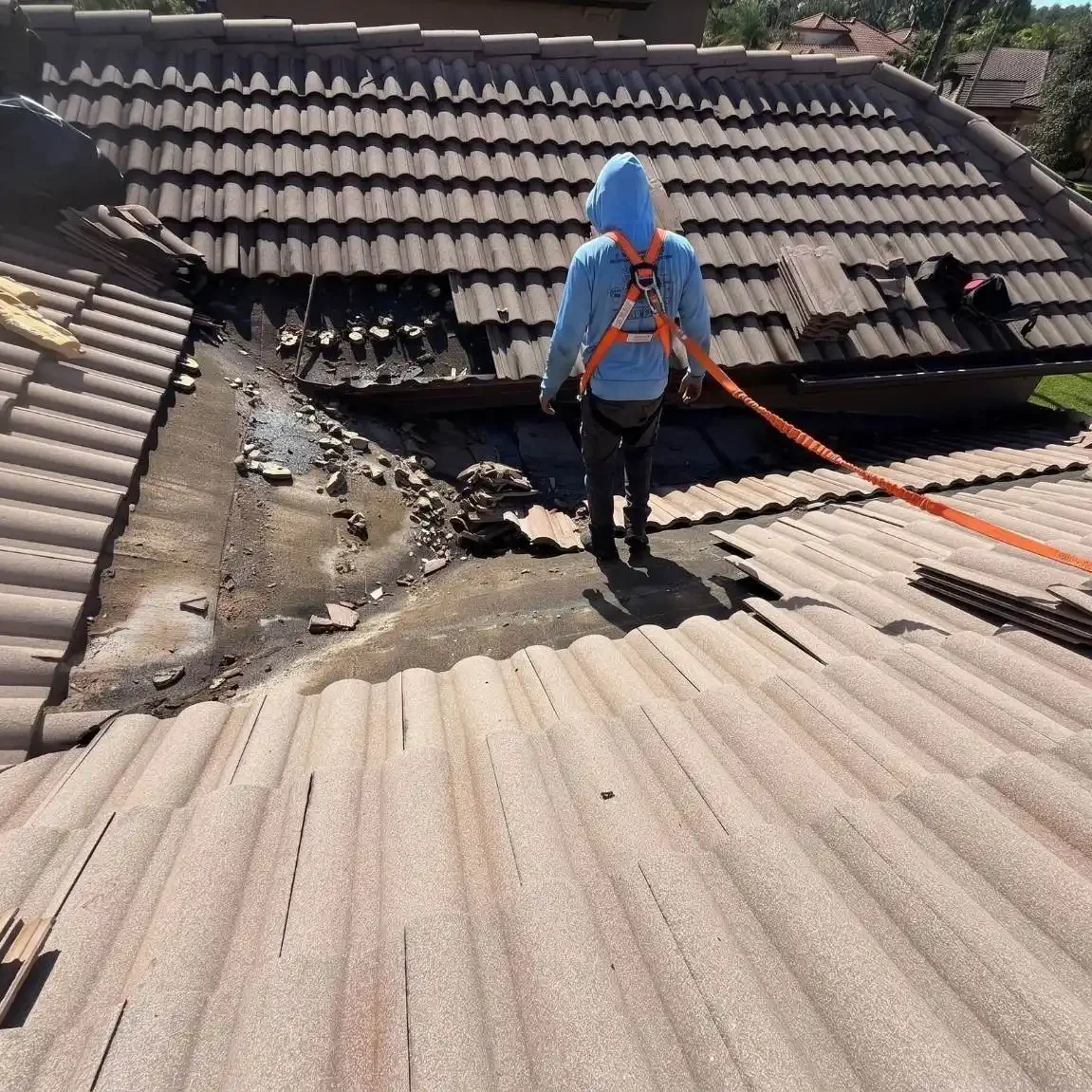Professional roofer inspecting and repairing a leaking tile roof valley with damaged underlayment on a residential home.