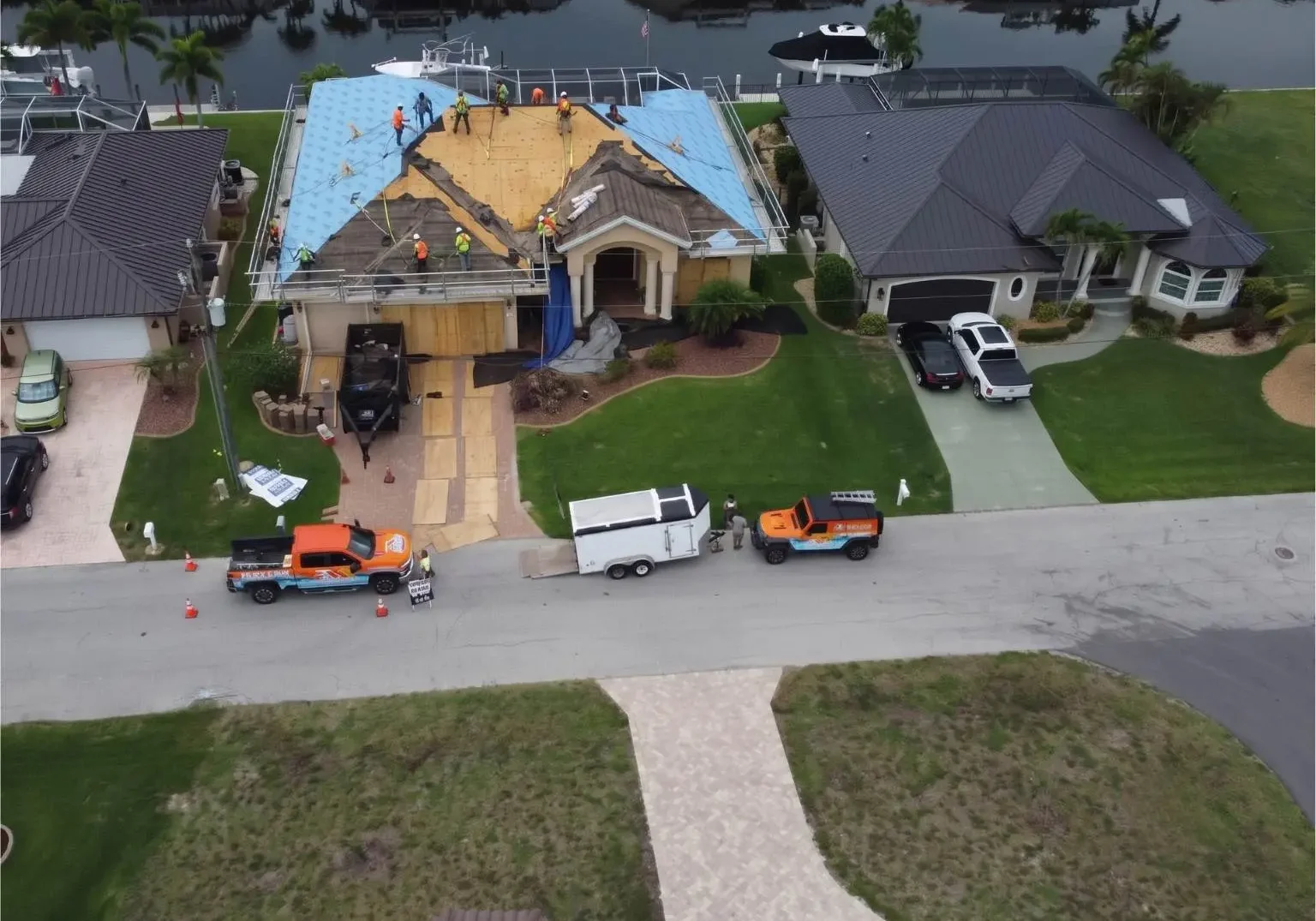 Full aerial neighborhood view showing Legrand's Roofing service trucks and an active underlayment installation on the 217 re-roofing site.