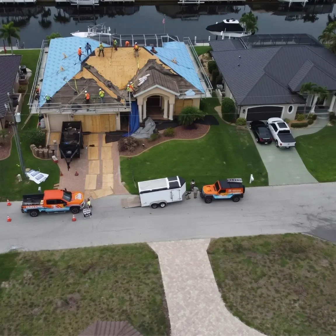 Full aerial neighborhood view showing Legrand's Roofing service trucks and an active underlayment installation on the 217 re-roofing site.