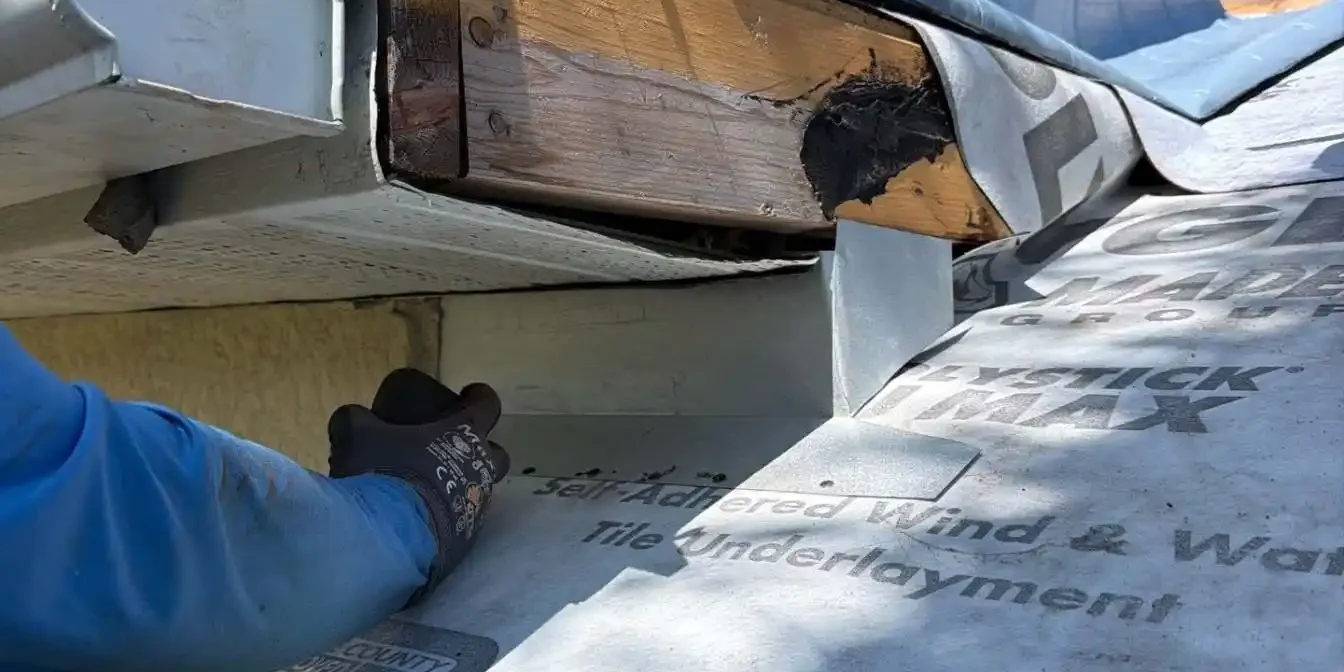 LeGrand's Roofing contractor carefully sealing and securing the waterproof underlayment membrane over the structural fascia wood framing.