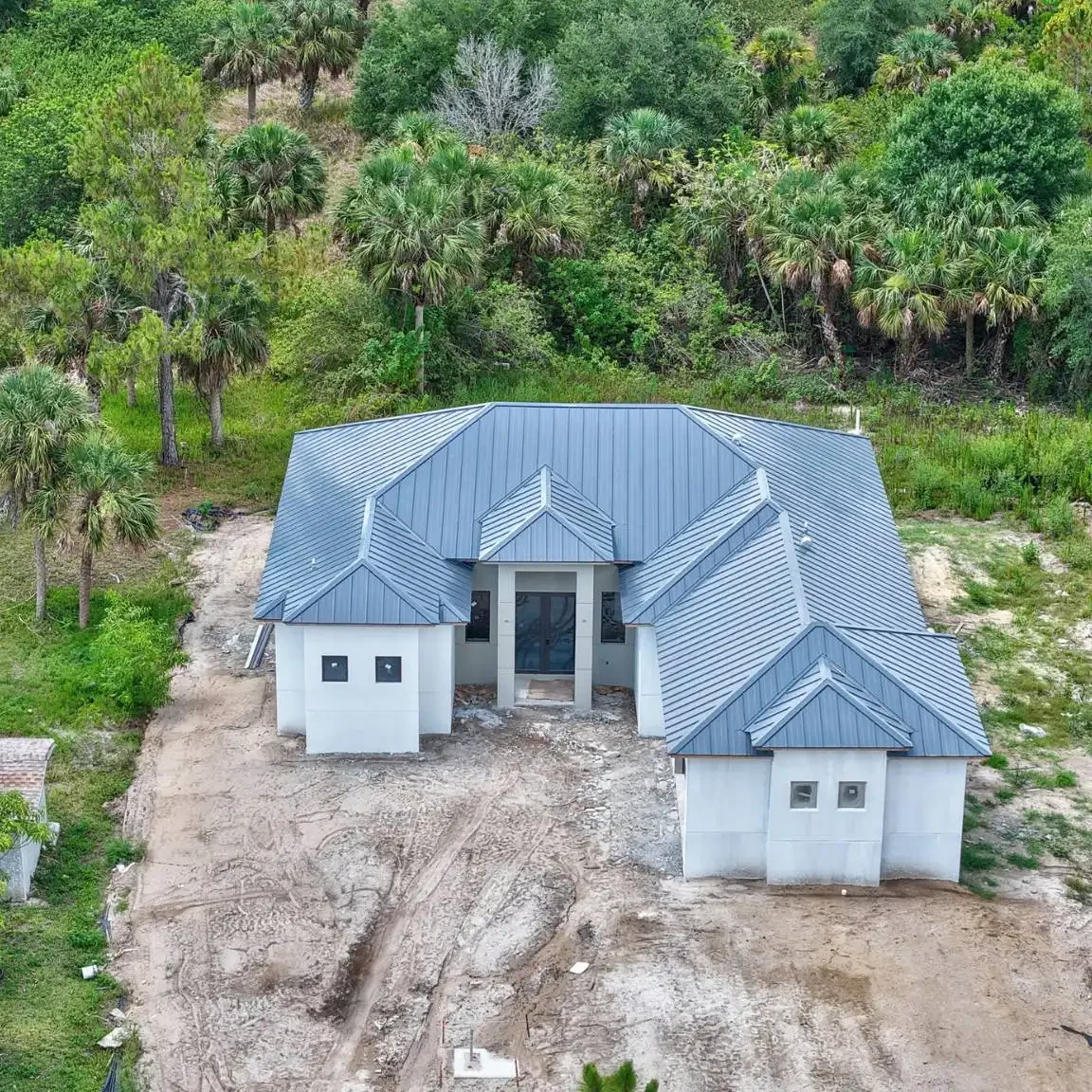 Aerial view of a modern new construction home featuring a durable standing seam metal roofing system installed in Sarasota County.